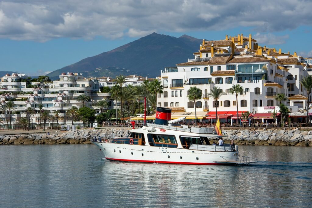 Classic white motor yacht sailing in Puerto Banus marina with white luxury apartments and La Concha mountain in the background