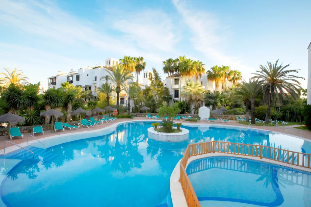 Ona Alanda Club Marbella outdoor swimming pool surrounded by palm trees and white apartments