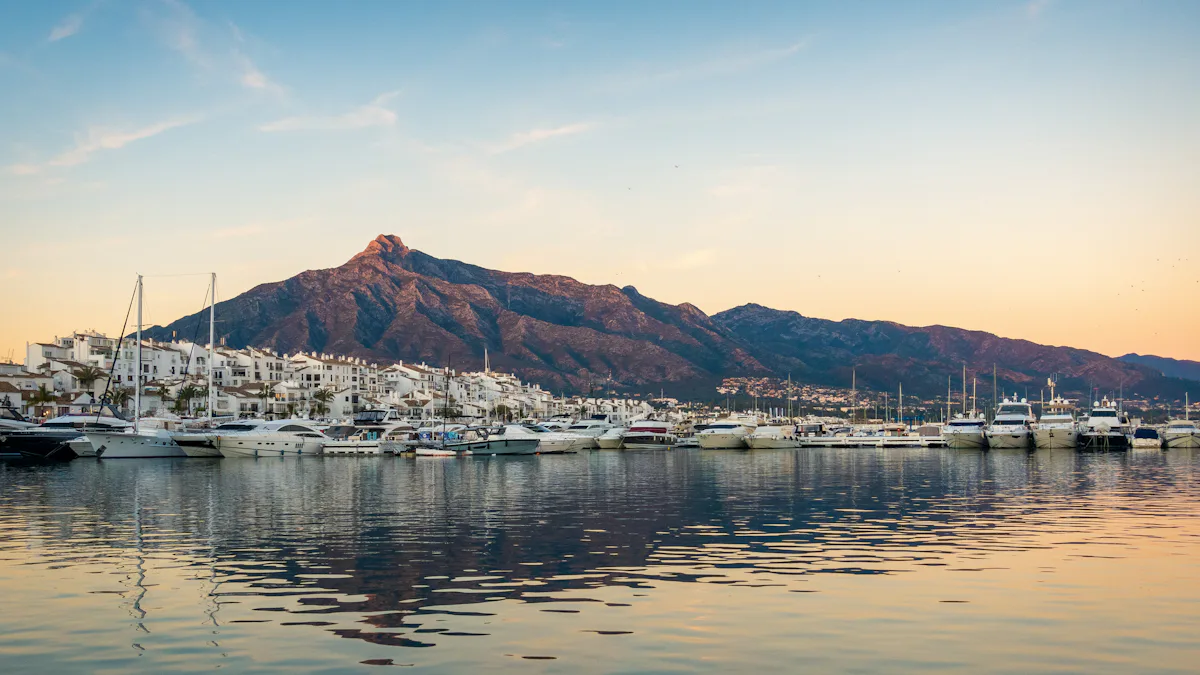 White boats moored in a Marbella harbour with mountains behind at golden hour