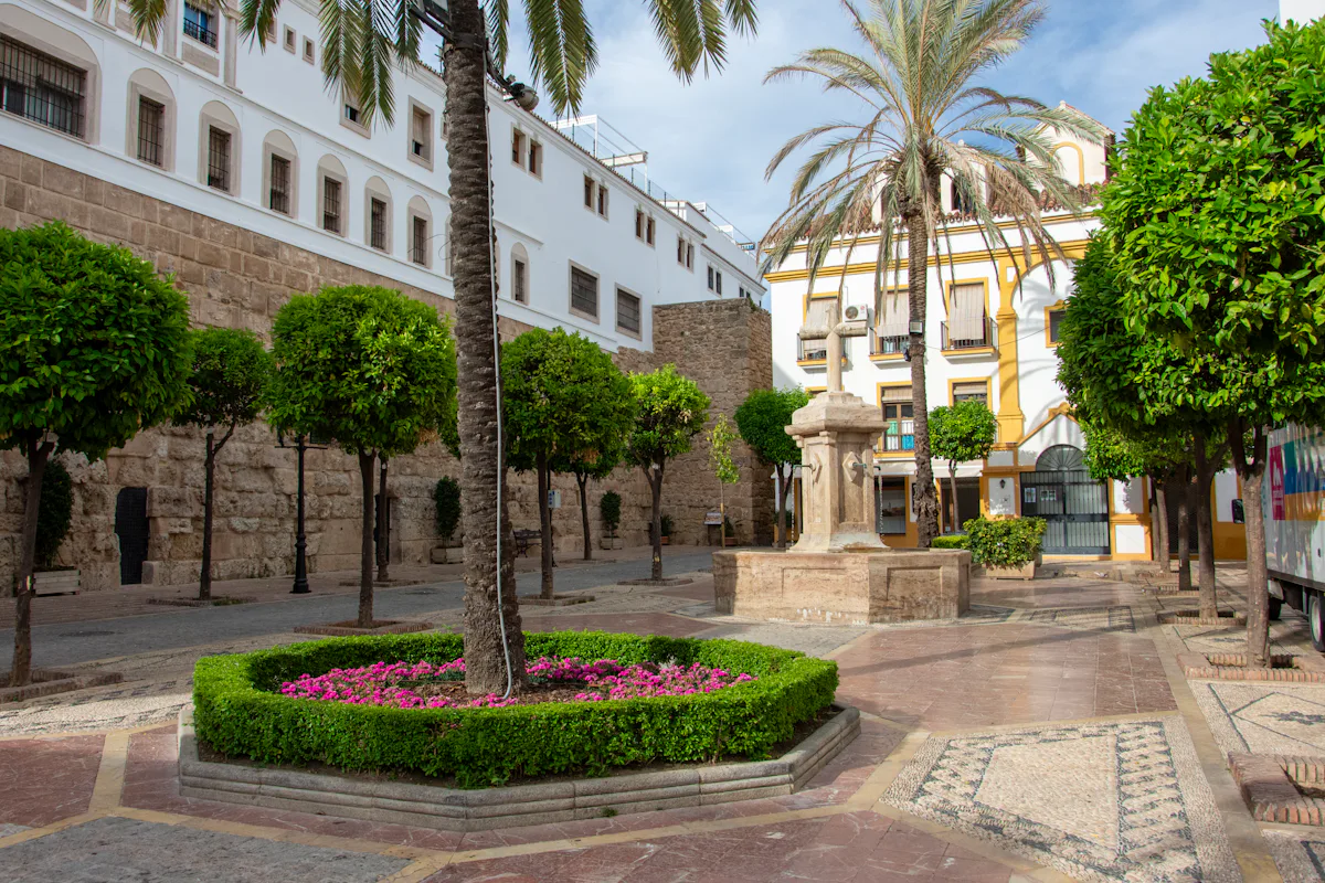 Old Town square with palm trees, a fountain and white buildings in Marbella
