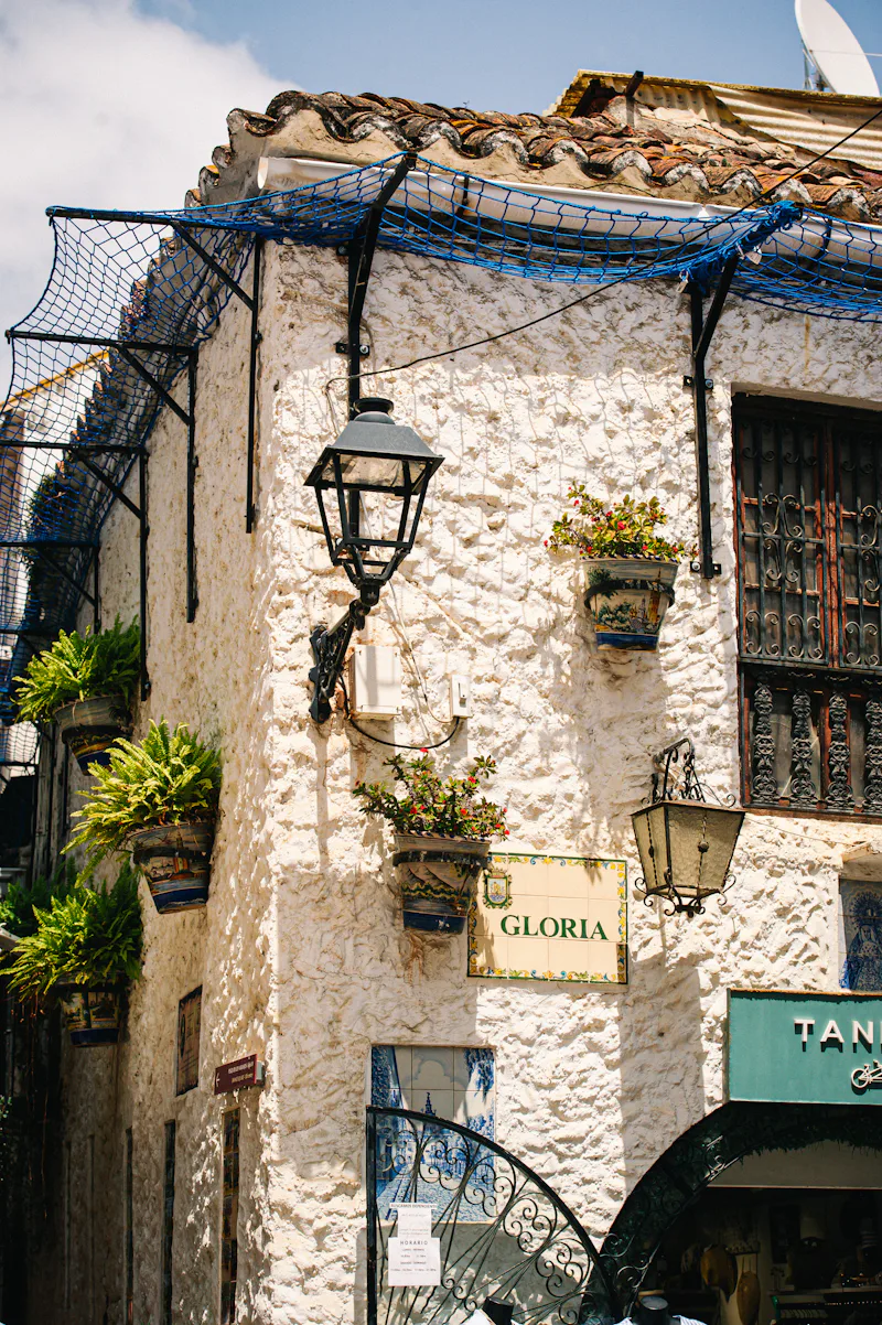 Corner of a whitewashed house with plants and lanterns in Marbella Old Town