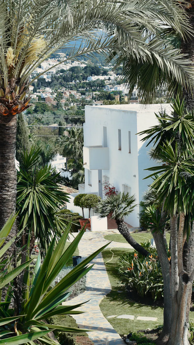 White hotel building framed by palm trees in Marbella