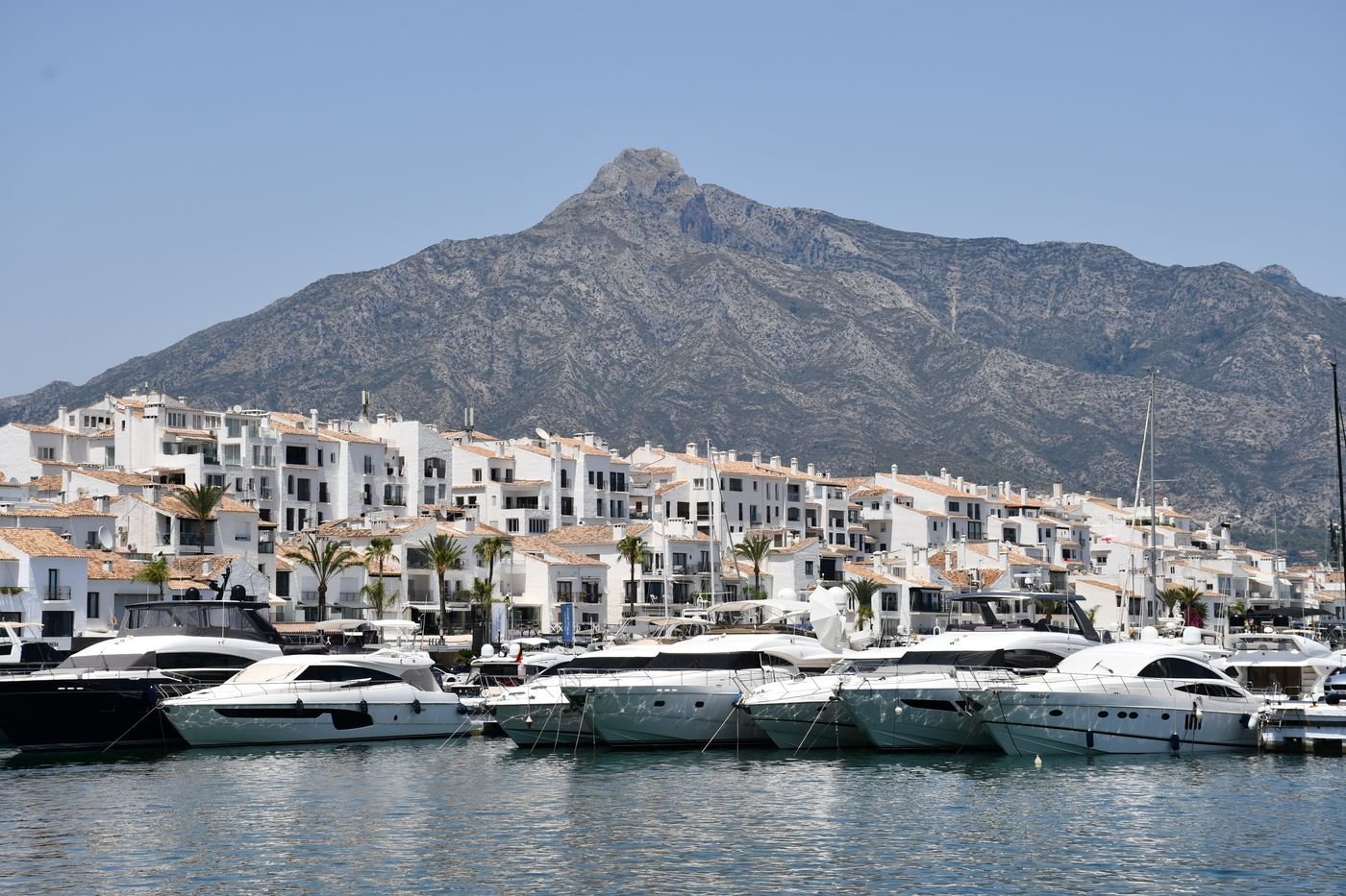 Luxury yachts moored in Puerto Banús harbour with mountains behind