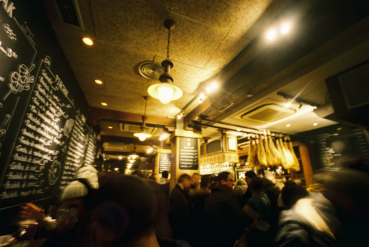 Lively Spanish tapas bar with hanging hams and warm lights