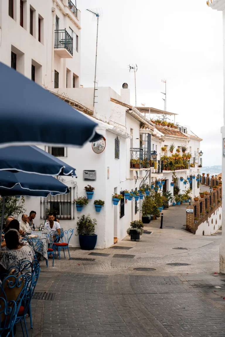 Mijas Pueblo: whitewashed street with restaurant terraces and umbrellas
